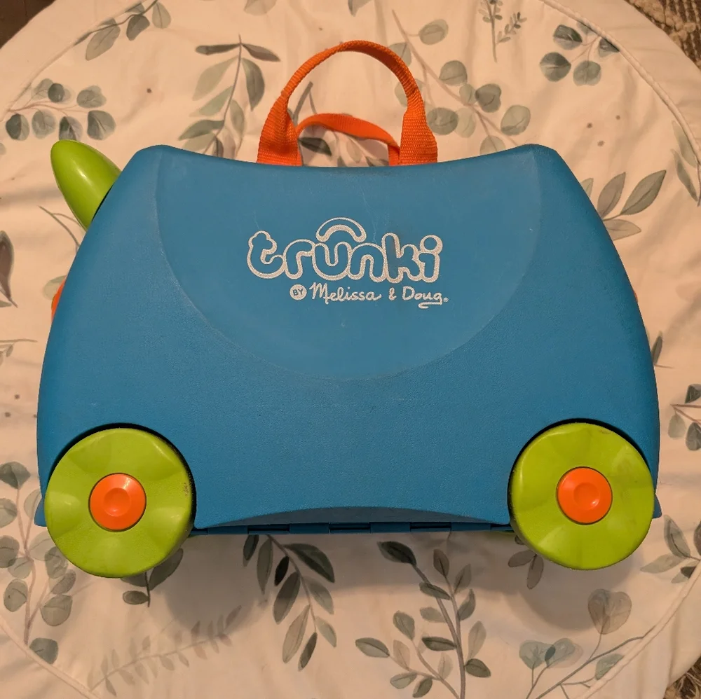 Melissa & Doug blue ride-on Trunki with green wheels and orange handle